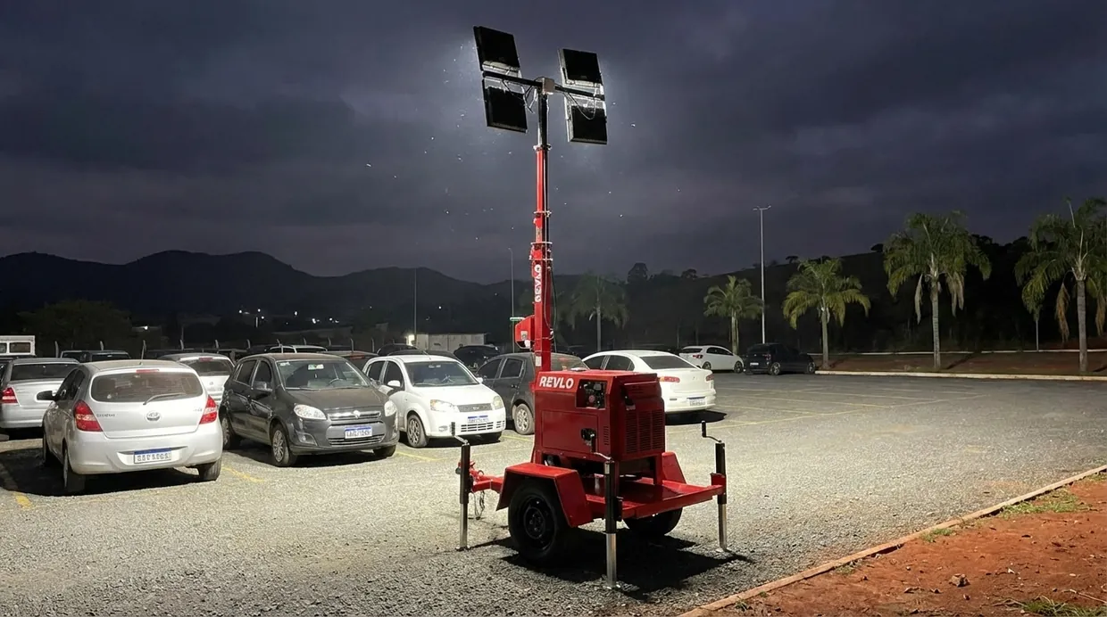Torre de iluminação acesa iluminando um pátio à noite